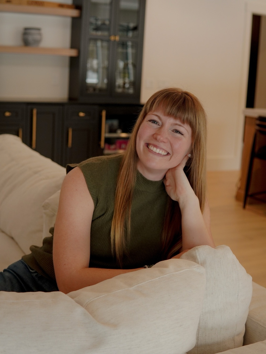 Portrait of Tia Gilbert seated on a cream sofa in a warm modern interior